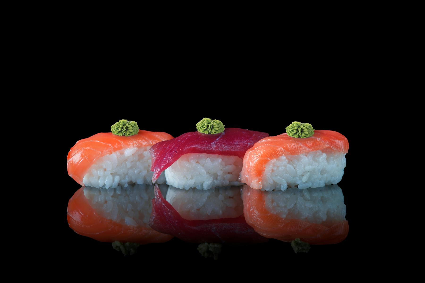 Nigiri on a dark lacquered surface, caught in low light