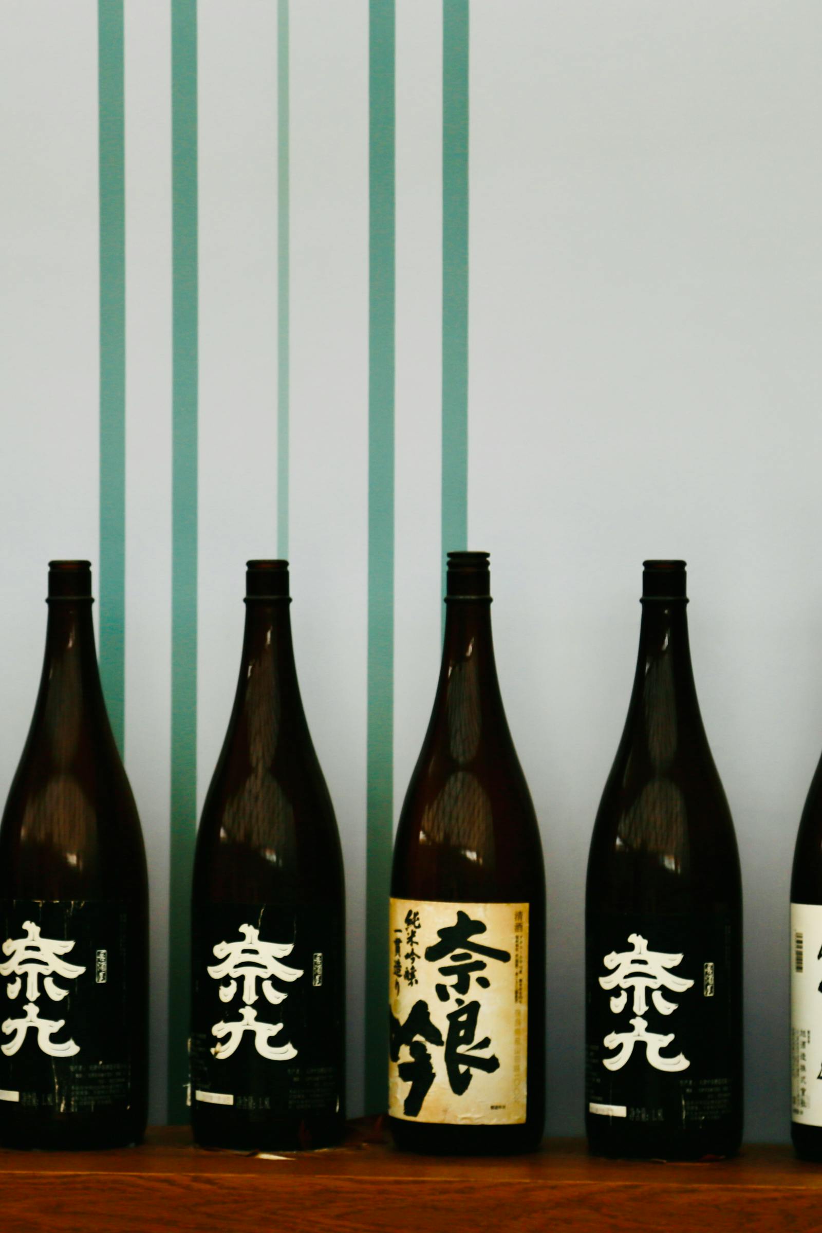 Sake bottles arrayed on a cedar shelf